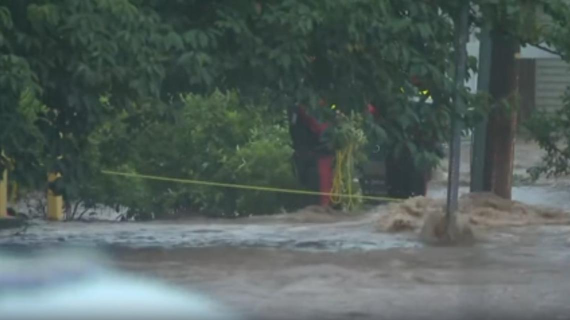 Crews use rope to pull man out of car through the raging floodwaters in